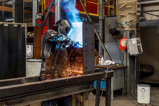 Personnel de l'atelier en train de souder un élément sur une charpente métallique